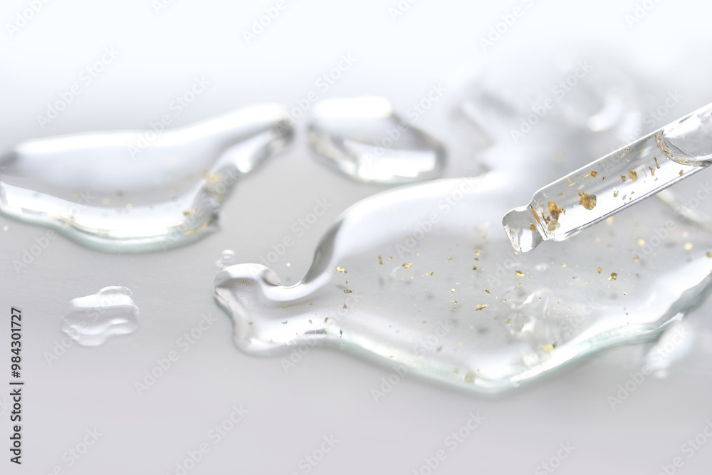 Luxurious gold-infused serum drops with glittering particles on smooth surface for skincare and beauty. Luxurious gold-infused serum drops with glittering particles on smooth surface for skincare and beauty.