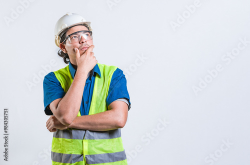 Pensive builder man with hand on chin isolated. Young builder wondering looking up with hand on chin