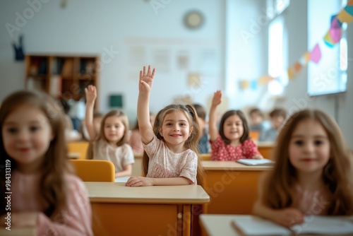Cheerful diverse primary school children students in modern light classroom with one hand up to asnwer teacher's question photo