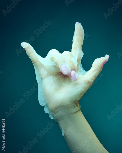 Female hand covered in slime, gesturing against cyan green background. Halloween party invitation, horror movie posters. Concept of Halloween theme, holiday. Copy space for ad photo