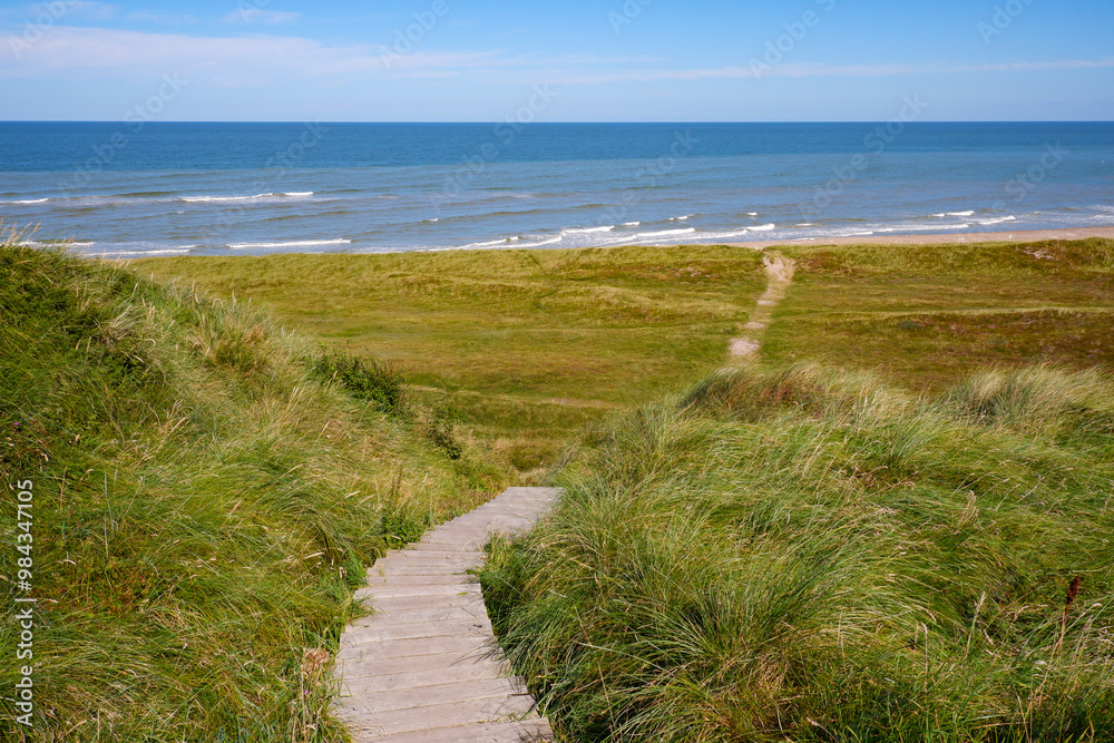 Danish Coastal Landscape. Hilly coast of the northern sea. Sun, blue sky, clouds, waves and grass. Beautiful landscape summer on the northern sea Danish Coastal Landscape. Hilly coast of the northern sea. Sun, blue sky, clouds, waves and grass. Beautiful landscape summer on the northern sea