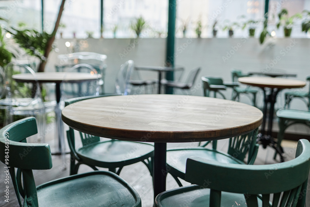 Medium close up of round wooden table with turquoise chairs in cafe Medium close up of round wooden table with turquoise chairs in cafe