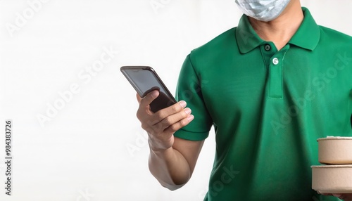 Delivery man in green shirt uses phone while holding a box. photo