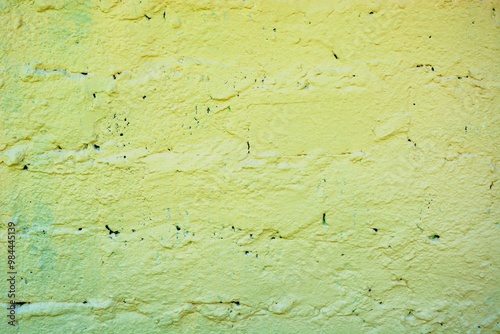 Retro wall painted with modern bright yellow green paint. Ugly arranged bricks on the wall. photo