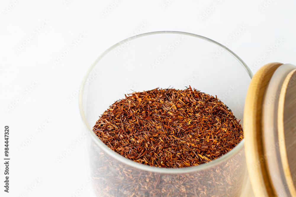 rooibos tea in a glass opened jar with wooden cap isolated on white background rooibos tea in a glass opened jar with wooden cap isolated on white background