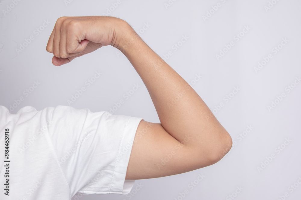 Male arm gesture wearing white t-shirt with muscles isolated on white background. Close up of male hand showing arm muscle strength. Male arm gesture wearing white t-shirt with muscles isolated on white background. Close up of male hand showing arm muscle strength.