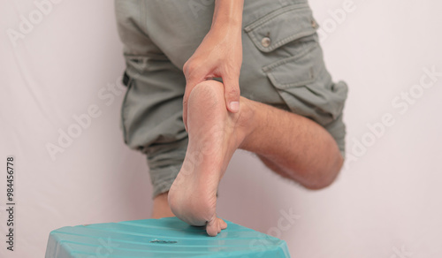 Inflammation of the ankle held by hand. Pain attacks a young man's ankle. health concept on leg bones.Ankle pain holding his aching leg - body pain concept.