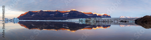 A panorama of Vikinge Bay, Scoresby Sund, Greenland, showing icebergs, mountains, a glacier, and polar bears on the moraine to the right. photo