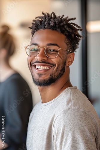 Friendly young diverse male worker sitting with colleagues in office, career progression and business theme.