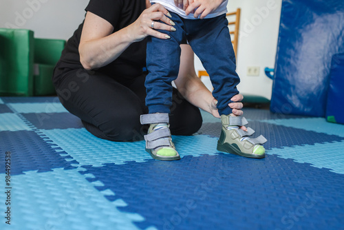 Young boy receives supportive assistance during a physical rehabilitation session aimed at improving mobility and strength photo