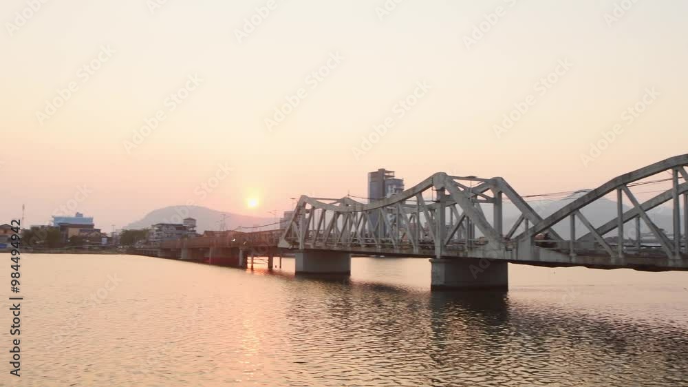 Kampot, Cambodia - 15th april, 2024: vehicles drive on The old iron Kampot Railway Bridge over Preaek Tuek Chhu River on sunset. Rainbow Bridge or Old Bridge. Built during French colonial times Kampot, Cambodia - 15th april, 2024: vehicles drive on The old iron Kampot Railway Bridge over Preaek Tuek Chhu River on sunset. Rainbow Bridge or Old Bridge. Built during French colonial times