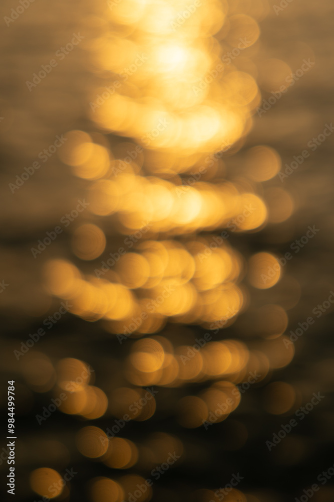 Fototapeta premium Blurred background, water of sea or ocean with sun light Bokeh reflecting or sparkling glitter during sunrise.
