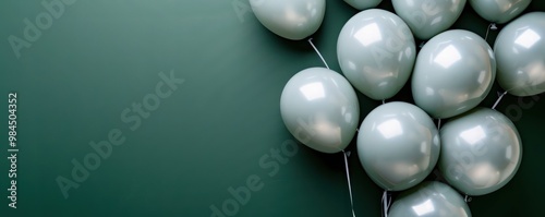 Top view of light grey balloons on a dark green background, perfect for a birthday greeting with room for text.