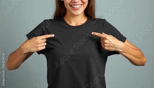 a smiling woman points at the front of her plain black crewneck t-shirt, t-shirt mockup
