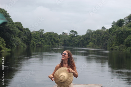 mulher com vestido claro e chapéu na beira de rio em hotel de selva em alta floresta, mato grosso  photo