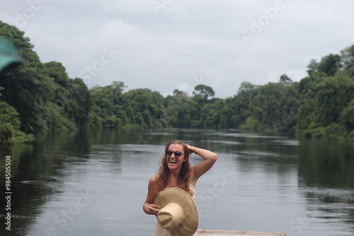 mulher com vestido claro e chapéu na beira de rio em hotel de selva em alta floresta, mato grosso  photo