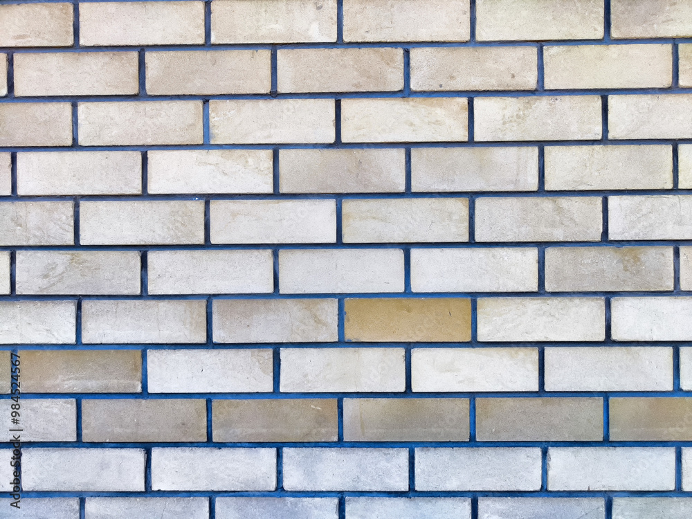 Obraz premium Textured brick wall with varying shades and subtle blue grout lines in natural light
