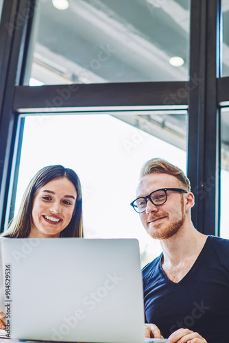 Happy smiling male and female hipsters enjoying video conversation with friends using web camera on netbook, carefree man and woman reading positive news in social networks connected to 4g internet