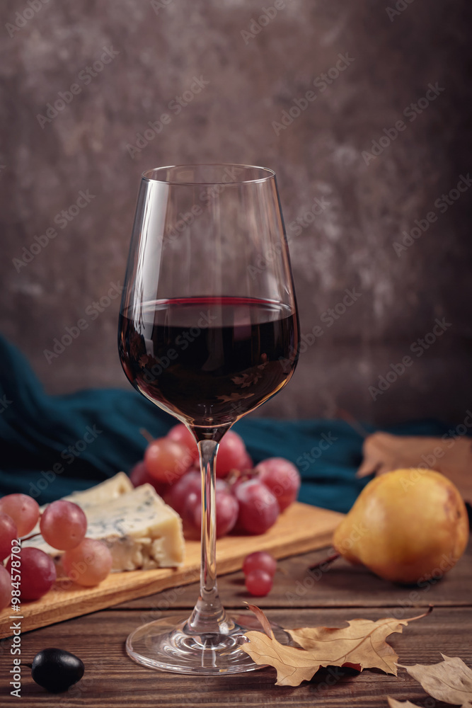Glass of red wine served with blue cheese on dark wooden background. Autumn picnic with wine and cheese platter, fruits and dry leaves in rustic style Glass of red wine served with blue cheese on dark wooden background. Autumn picnic with wine and cheese platter, fruits and dry leaves in rustic style
