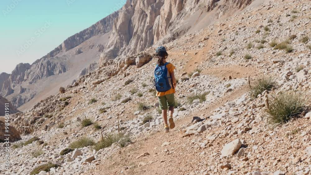 happy child in the mountains. a boy with a backpack walks along a path in the mountains. hiking in the mountains. happy child in the mountains. a boy with a backpack walks along a path in the mountains. hiking in the mountains.