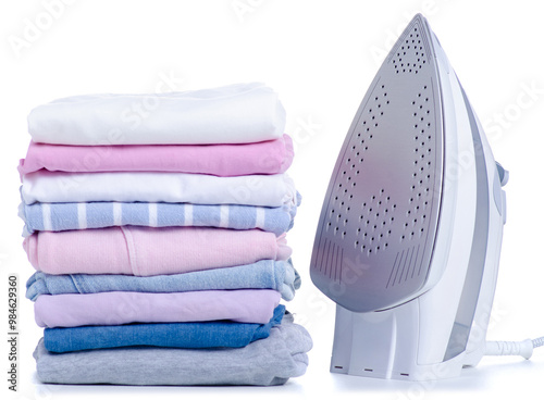 Stack pile of colorful clothes and electric iron on white background isolation