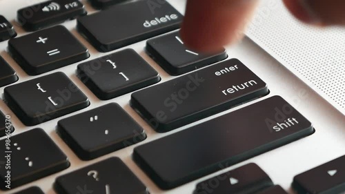 Slow motion of forefinger pressing enter key on modern laptop computer keyboard, extreme closeup macro detail, shallow DOF, one person. Sending messages, purchasing, receiving rules, executing program