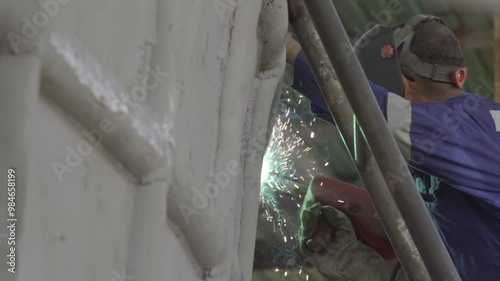 A welder with all necessary safety equipment, welding metal parts of a boat photo