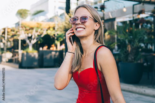 Cheerful blonde chatting on phone on street