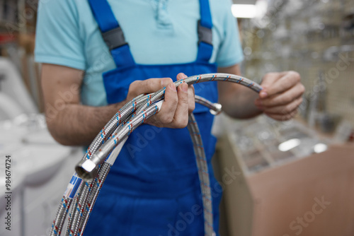 Cropped shot of man plumber holding plumbing hoses at shopping mall photo