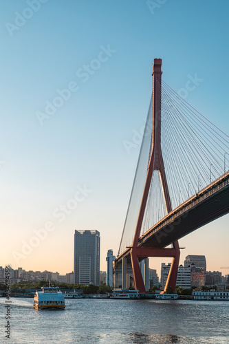 Yangpu Bridge and a ferry on the Huangpu River in Shanghai at dusk. photo