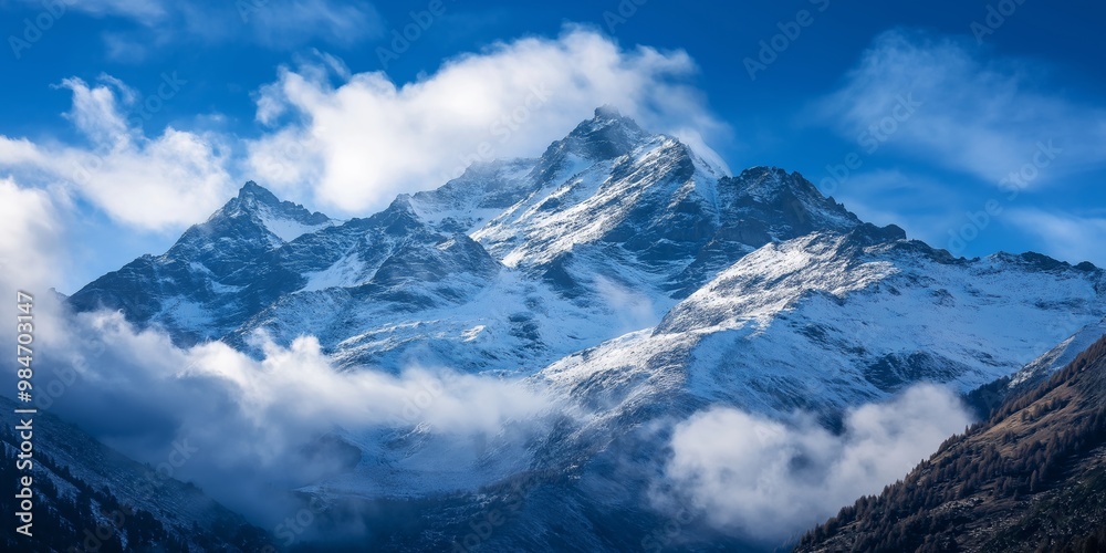 A breathtaking view of snow-covered mountains shrouded in clouds, juxtaposed with a vibrant blue sky, showcasing nature's grandeur. A breathtaking view of snow-covered mountains shrouded in clouds, juxtaposed with a vibrant blue sky, showcasing nature's grandeur.