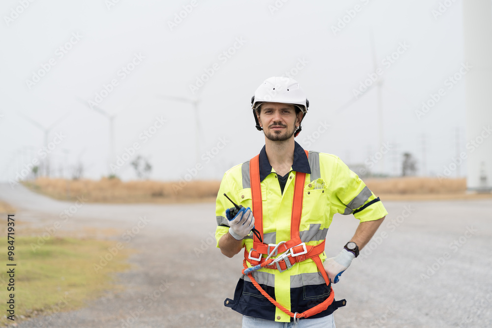 Male engineer working and inspecting quality of wind turbines at windmill field farm. Male engineer repairing or maintaining wind turbines at wind turbines farm