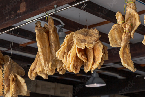 Dried salted fish hanging from the ceiling beams in a rustic market stall, showcasing the traditional drying and preservation methods of seafood. photo