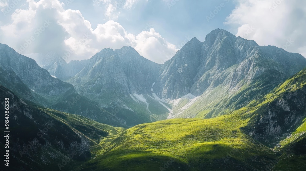 Fototapeta premium Stunning mountain landscape with lush green valleys and towering peaks under a partly cloudy sky.