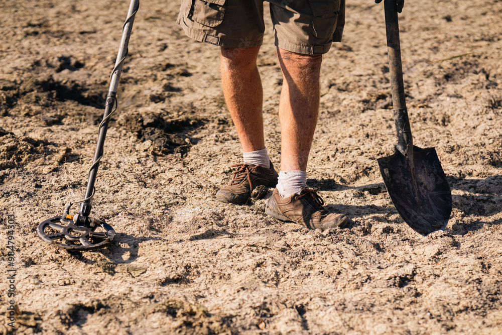 A man with a metal detector looking for antique valuables in the ground. A man with a metal detector looking for antique valuables in the ground.