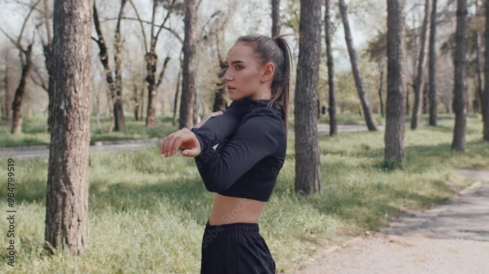Young woman engaging in arm stretches amidst park's natural beauty Young woman engaging in arm stretches amidst park's natural beauty