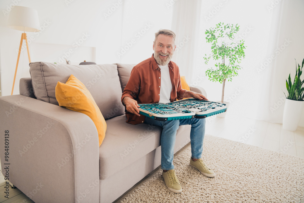 Full size photo of nice pensioner man sit couch tools mechanic set dressed brown garment spend pastime spacious house indoors room Full size photo of nice pensioner man sit couch tools mechanic set dressed brown garment spend pastime spacious house indoors room