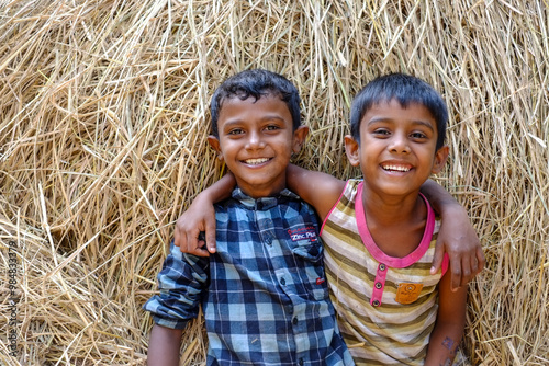 South asian young rural boys having fun together jumping in a haystack 