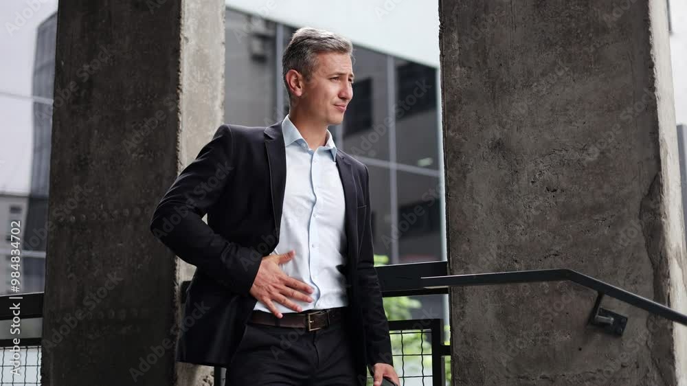 A middle-aged businessman standing alone outside his office building, holding his stomach in pain. He is experiencing severe discomfort and indigestion, possibly from stress or an unhealthy lifestyle. A middle-aged businessman standing alone outside his office building, holding his stomach in pain. He is experiencing severe discomfort and indigestion, possibly from stress or an unhealthy lifestyle.