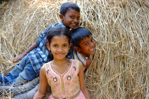 South asian young rural kids having fun together jumping in a haystack 