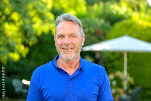 Portrait of a Smiling Mature Man in a Blue Polo Shirt Outdoors