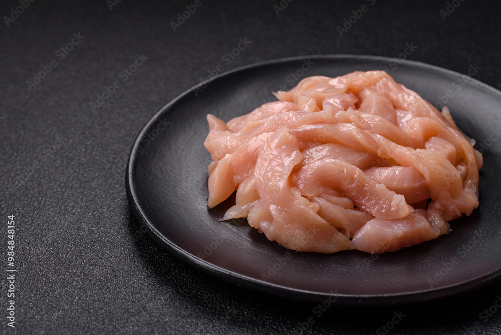 Raw chicken fillet cut into strips with spices and herbs Raw chicken fillet cut into strips with spices and herbs
