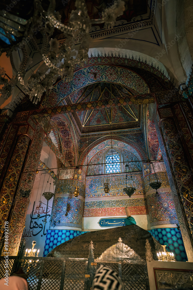 The ornate interior of a mosque in Konya, Turkey, featuring intricate tilework, calligraphy, and a domed ceiling.