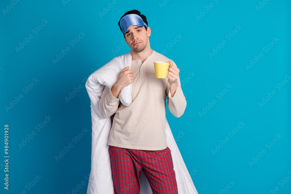 Photo portrait of nice young male hold duvet coffee mug wear nightwear sleepover good night isolated on blue color background Photo portrait of nice young male hold duvet coffee mug wear nightwear sleepover good night isolated on blue color background