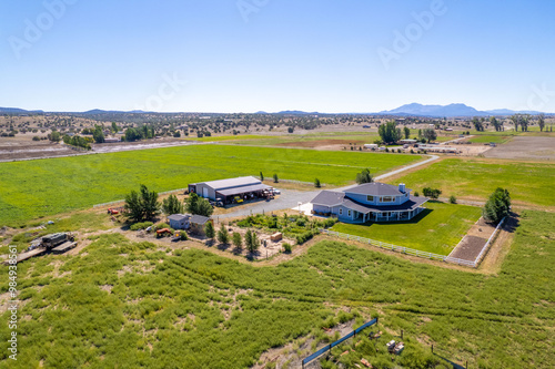 Spacious ranch property with modern home and expansive green fields near mountains