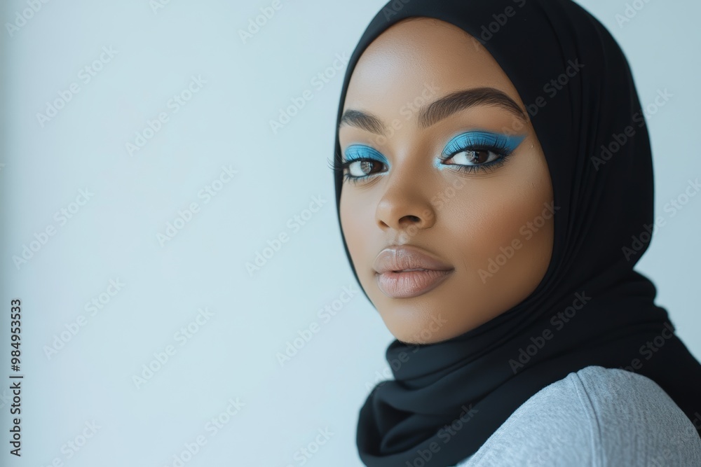 A confident woman showcases her bold blue eye makeup while wearing a stylish hijab, creating an elegant and modern look A confident woman showcases her bold blue eye makeup while wearing a stylish hijab, creating an elegant and modern look