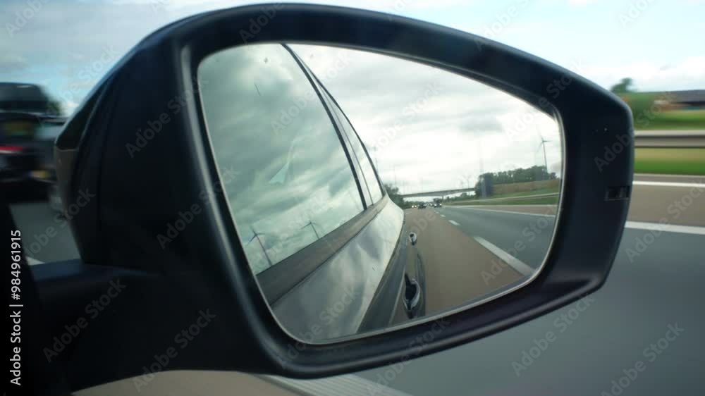 A car's rear view mirror shows a road with a truck in the distance. The mirror is reflecting the truck and the road, creating a sense of depth and distance A car's rear view mirror shows a road with a truck in the distance. The mirror is reflecting the truck and the road, creating a sense of depth and distance
