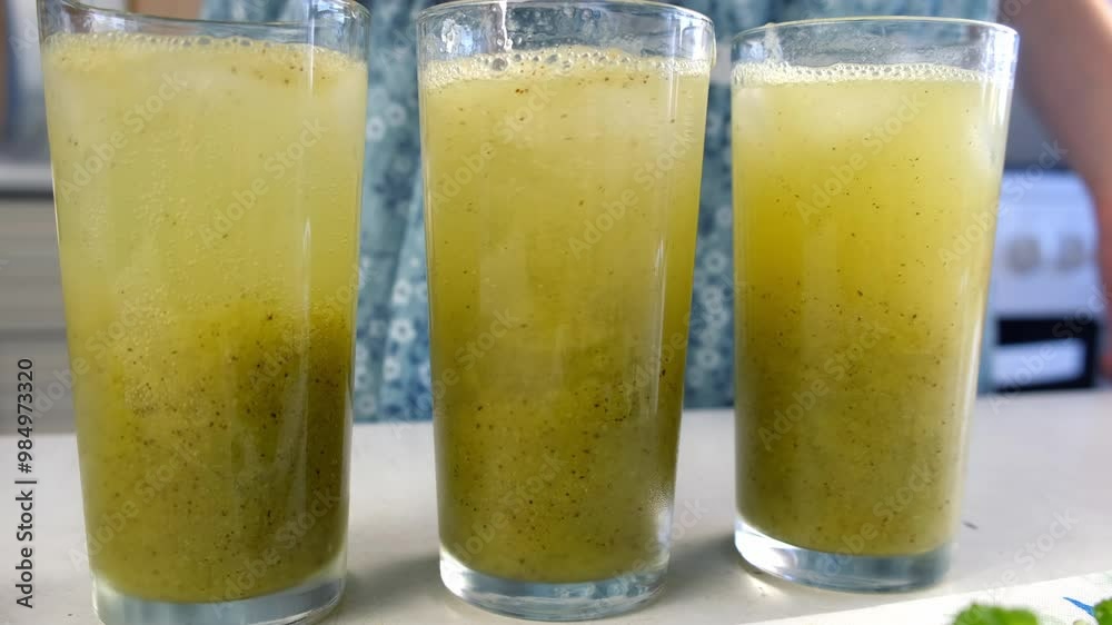 Mixing sparkling water with green kiwi puree preparing lemonade in glasses on kitchen at home. Recipe cuisine professional culinary. Prepare delicious fruit dessert homemade beverage drink. Mixing sparkling water with green kiwi puree preparing lemonade in glasses on kitchen at home. Recipe cuisine professional culinary. Prepare delicious fruit dessert homemade beverage drink.
