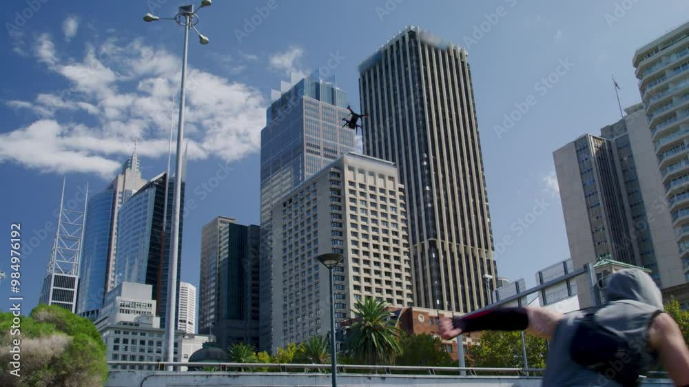 Hooded man with sunglasses running through city with small drone friend - low, steady cam