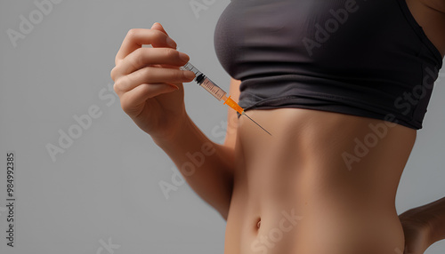 woman putting a hormonal injection in her stomach with pen syringe on a grey background. The use of lipolytics in cosmetology. Preparations for figure correction. Insulin injections for diabetes photo